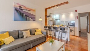 A living room with a sofa, a coffee table, and a painting of a pier.