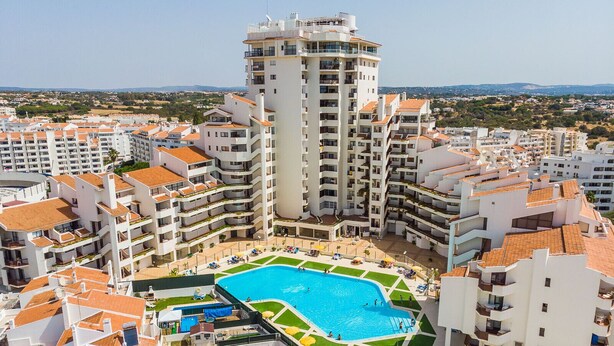 A high-rise hotel with a central swimming pool surrounded by balconies.
