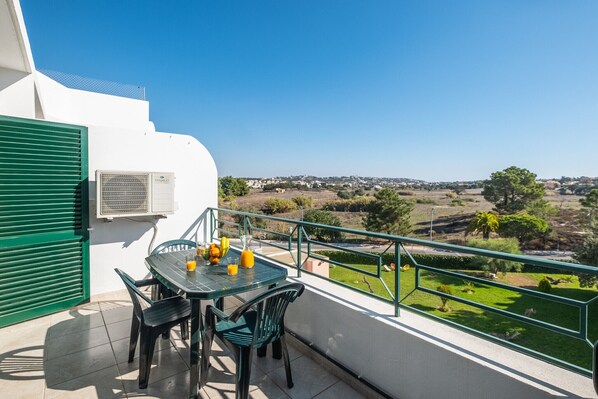A balcony with a table, chairs, and a view of a landscape. - #068 T1 Salgados by Home Holidays (Albufeira)
