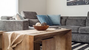 A living room with a grey sofa, blue cushions, a wooden coffee table, and a bowl with decorative items. - Ultimate Downtown Charlotte Oasis, 10 Guests (Charlotte)