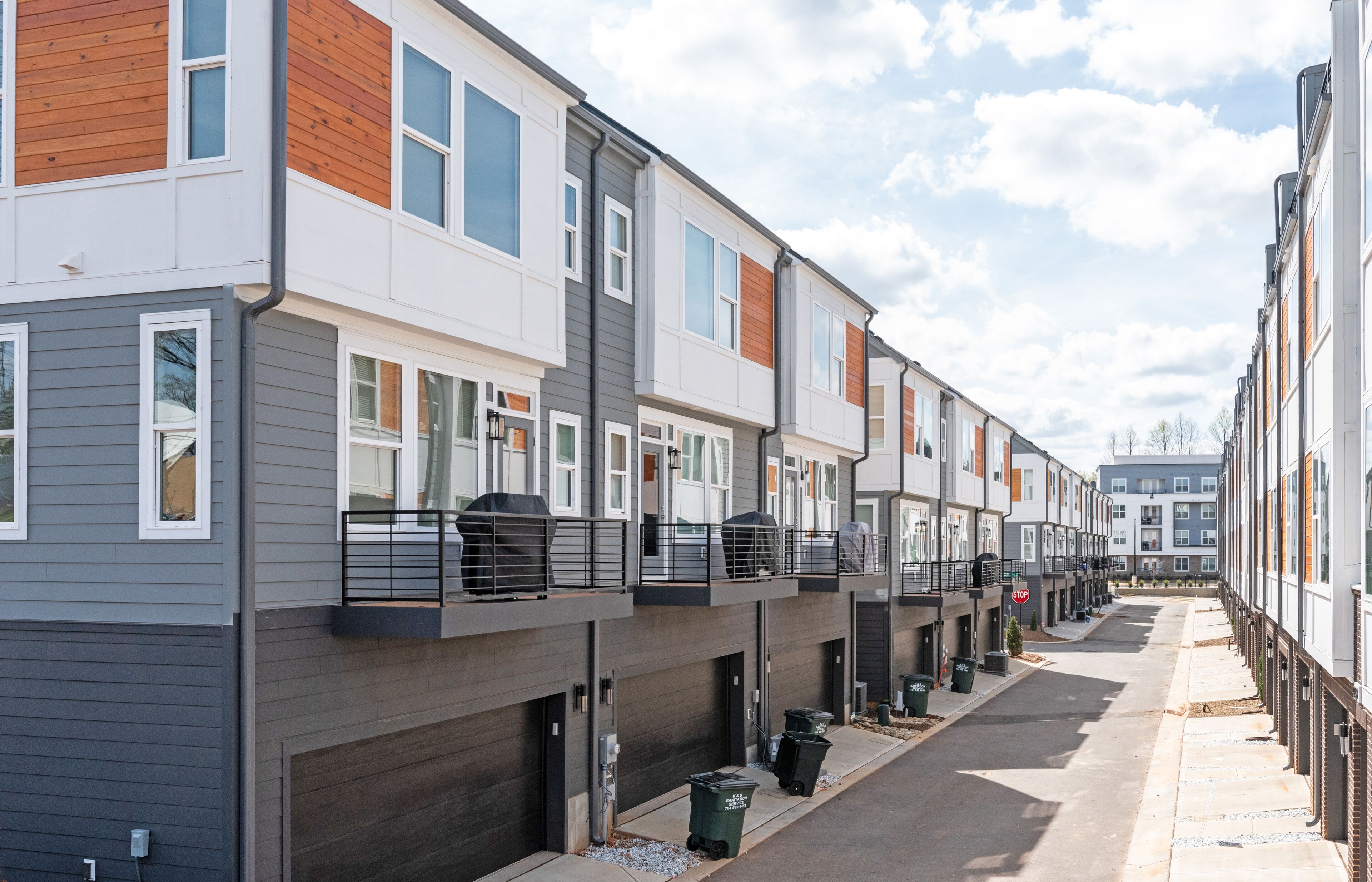 A row of townhouses with attached garages, a clear sky, and a quiet street.