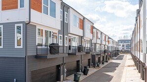 A row of townhouses with attached garages, a clear sky, and a quiet street. - Ultimate Downtown Charlotte Oasis, 10 Guests (Charlotte)