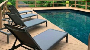 Un área de piscina con sillones de descanso y una terraza de madera.