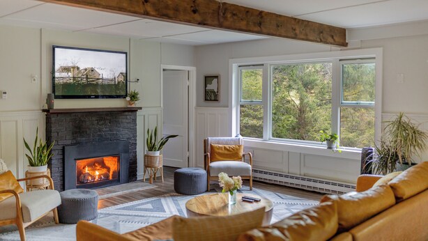 Una sala de estar acogedora con chimenea, asientos cómodos y ventanas amplias con vistas al exterior.
