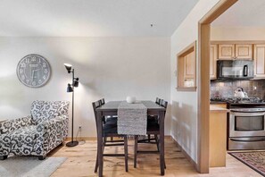 Un espace de vie compact comprenant un coin repas, un canapé, une horloge et une kitchenette.
