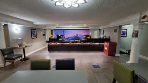 A hotel reception area with a modern design, featuring a reception desk, seating area, and a large screen displaying a cityscape.