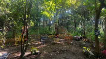 A forested area with a wooden fence, metal chairs, and a welcome sign.