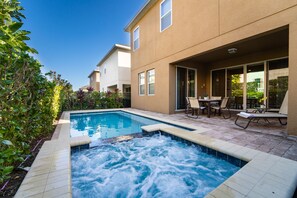 A residential pool area with a hot tub, outdoor seating, and a view of neighboring houses. - Amazing Home With Spa & Games Room In Gated Resort Close to WDW (Kissimmee)