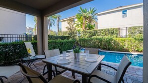 An outdoor patio with a pool, tables, and chairs. - Amazing Home With Spa & Games Room In Gated Resort Close to WDW (Kissimmee)