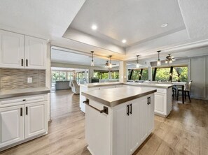 A spacious kitchen with a large island, white cabinetry, and pendant lighting. - Lily`s River Retreat | A Waterfront Escape (Anderson)