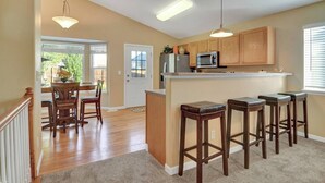 A kitchen with wooden cabinets, a microwave, and a bar area with stools. - 4 BED/2 BATH; Sleeps 10! CO Springs- fenced yard, pets w/fee, Great for Families (Colorado Springs)