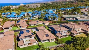 Zona residencial con casas equipadas con paneles solares, un campo de golf y vista al océano.