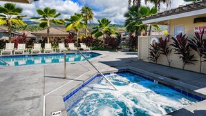 Un área de piscina con sillas de descanso, un jacuzzi y palmeras.