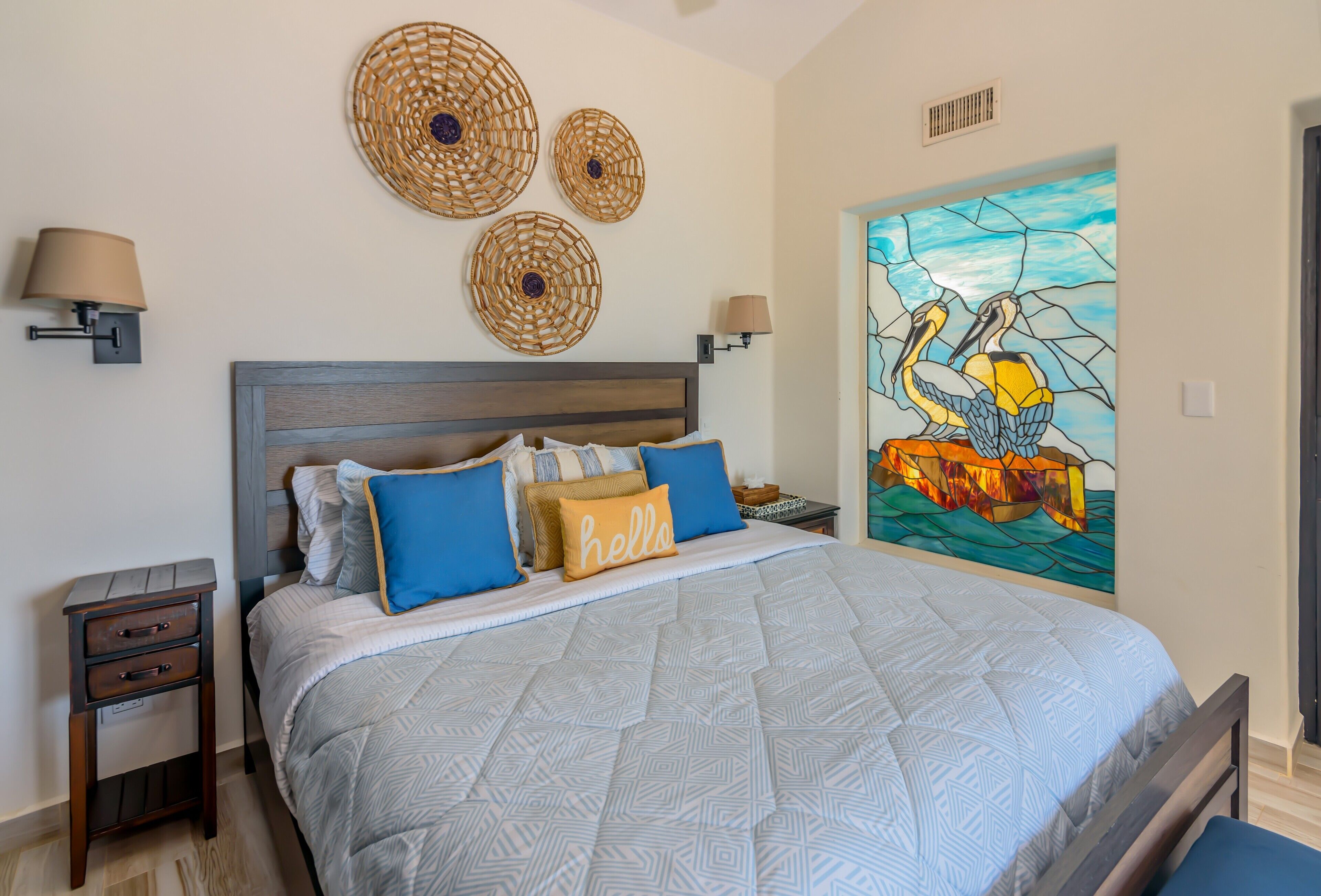 Une chambre à coucher avec un lit, des tables de chevet, des œuvres d’art murales et un tableau.