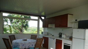 Una cocina con armarios de madera, un refrigerador blanco, un microondas y una mesa de comedor con sillas.