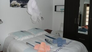 Un dormitorio con cama, mesita de noche, silla, armario y espejo.
