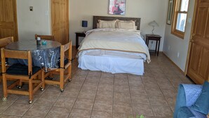 A bedroom with a bed, a table with chairs, a lamp, and a painting on the wall. - Studio apartment 15 minute walk to the plaza (Santa Fe)