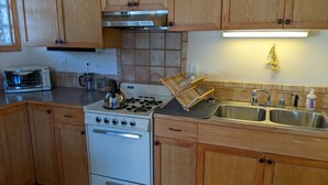 A kitchen with wooden cabinets, a gas stove, a sink, and a toaster. - Studio apartment 15 minute walk to the plaza (Santa Fe)