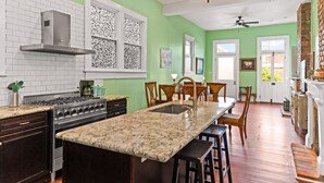 A kitchen with a large island, a stove, and a chandelier.