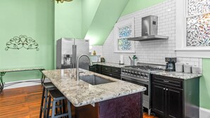 A modern kitchen with a central island, stainless steel appliances, and a decorative metal wall piece.