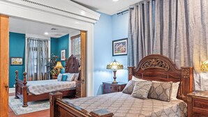 A bedroom with two beds, a wooden headboard, a nightstand, a lamp, and a framed picture on the wall.