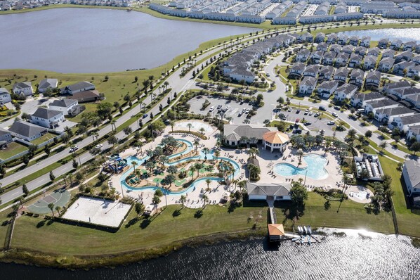 An aerial view of a residential area with a swimming pool complex, houses, and a marina.