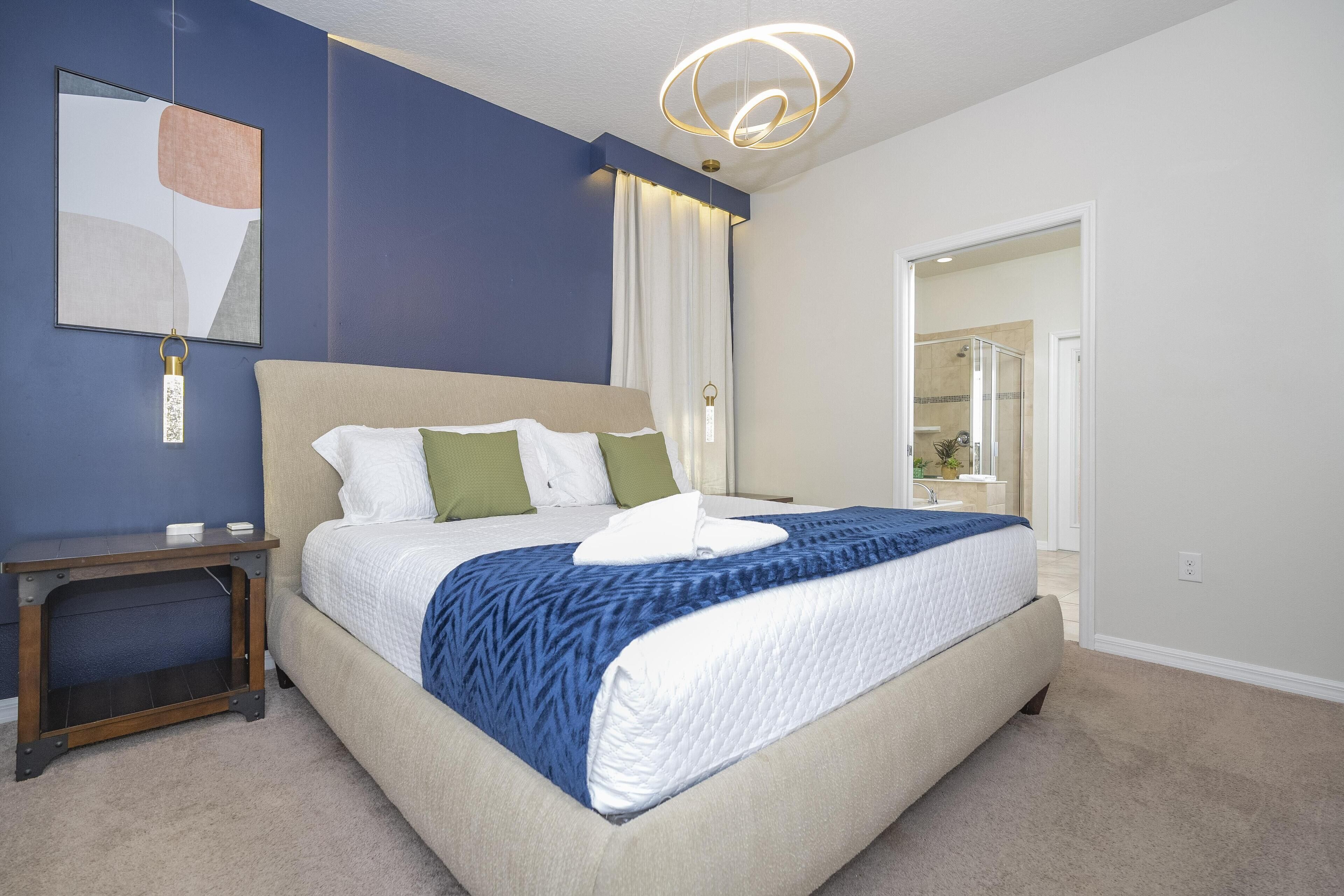 A bedroom with a bed, nightstand, and a hanging light fixture.