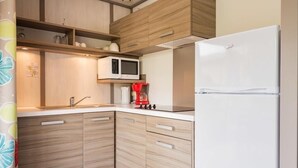 A modern kitchen with wooden cabinets, a white refrigerator, a microwave, and a coffee machine.