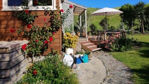 Une maison en bois dotée d’un patio avec jardin, d’un espace salon extérieur et d’une pergola avec un parasol.