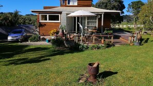 Une maison moderne avec une façade en bois, un porche abrité et une voiture garée dans l’allée.