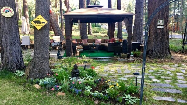 A gazebo with outdoor seating, surrounded by trees and a garden with colorful flowers. - HAKUNA MATATA  (South Lake Tahoe)