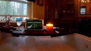 A bathroom with a bathtub, a window, a candle, and a book titled "Guided Meditation" on the counter. - HAKUNA MATATA  (South Lake Tahoe)