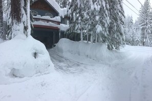 A snow-covered driveway leading to a wooden cabin with a red roof. - HAKUNA MATATA  (South Lake Tahoe)
