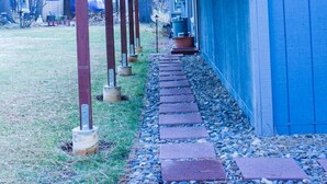 A covered outdoor area with a wooden roof supported by metal posts, leading to a building with a blue exterior. - HAKUNA MATATA  (South Lake Tahoe)