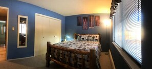 Un dormitorio con cama, armario y ventana con persianas.
