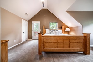 A bedroom with a wooden bed, a window, and a door.