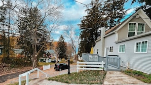 A residential area with a house featuring a front deck and a driveway. - Quiet renovated cottage by Seabreeze (Rochester)
