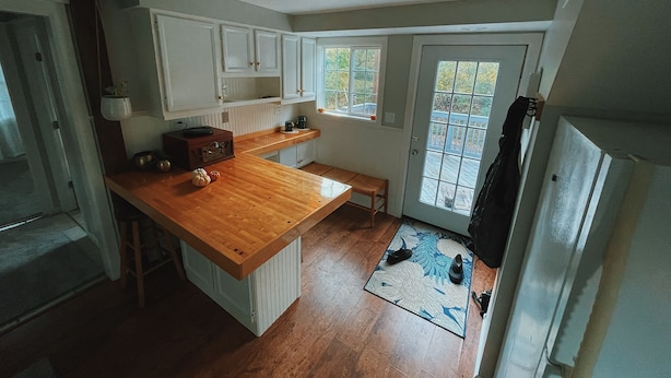 A kitchen with wooden countertops, white cabinets, a built-in oven, and a window with a view of the outdoors. - Quiet renovated cottage by Seabreeze (Rochester)