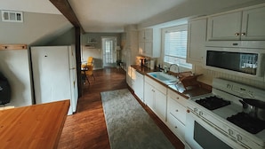 A kitchen with white cabinets, a stove, and a microwave. - Quiet renovated cottage by Seabreeze (Rochester)