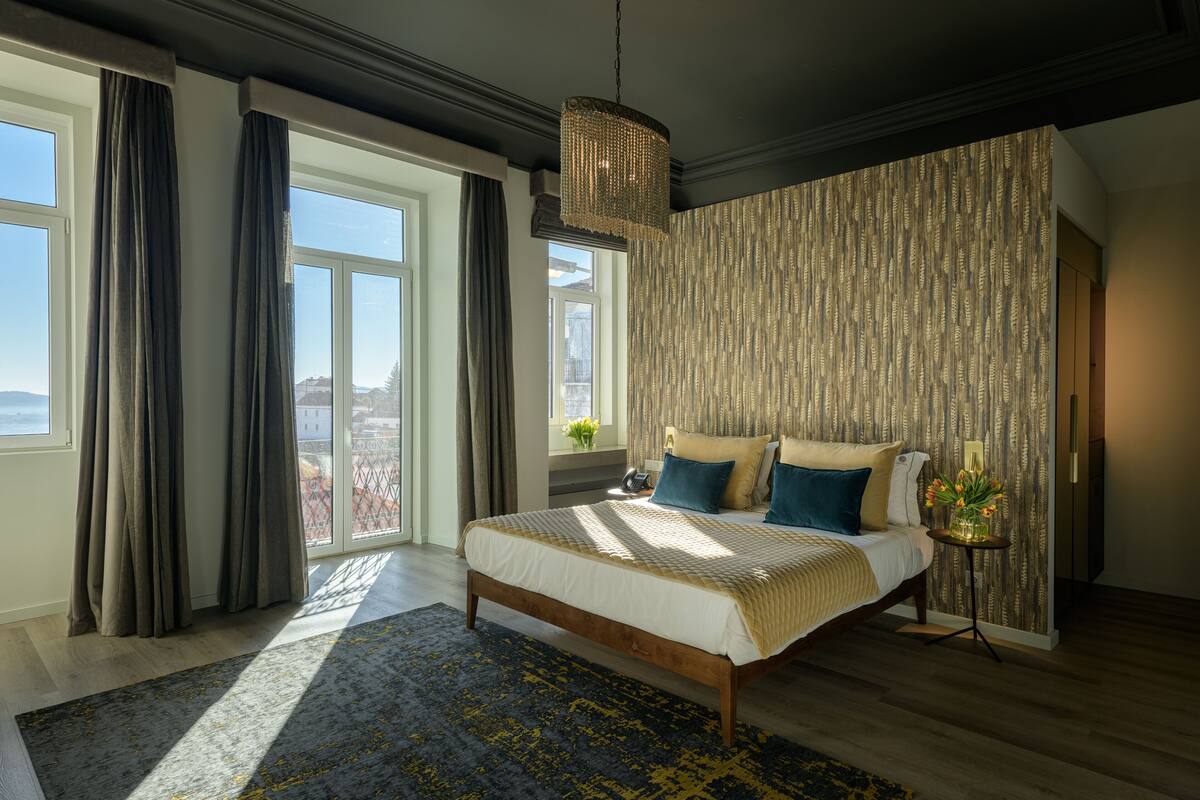 Ein Schlafzimmer mit einem großen Bett, einer Chandelier, Blick auf die Stadt und einer Wand mit Muster.