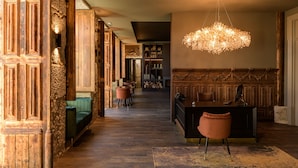 A hallway with wooden paneling, a green sofa, a desk with a chair, and a chandelier. - Pena D'Água Boutique Hotel & Villas  (Covilhã)
