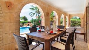 A dining area with a pool view, featuring a long wooden table with chairs, stone arches, and potted plants. - Luxury hideaway with 100m² pool in a green oasis (summer and winter) (Vallgornera)