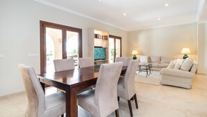 A dining area with a wooden table and chairs, a sofa, and a television in the background. - Luxury hideaway with 100m² pool in a green oasis (summer and winter) (Vallgornera)