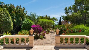 A stone pathway leading to a building, surrounded by lush greenery and flowering plants. - Luxury hideaway with 100m² pool in a green oasis (summer and winter) (Vallgornera)