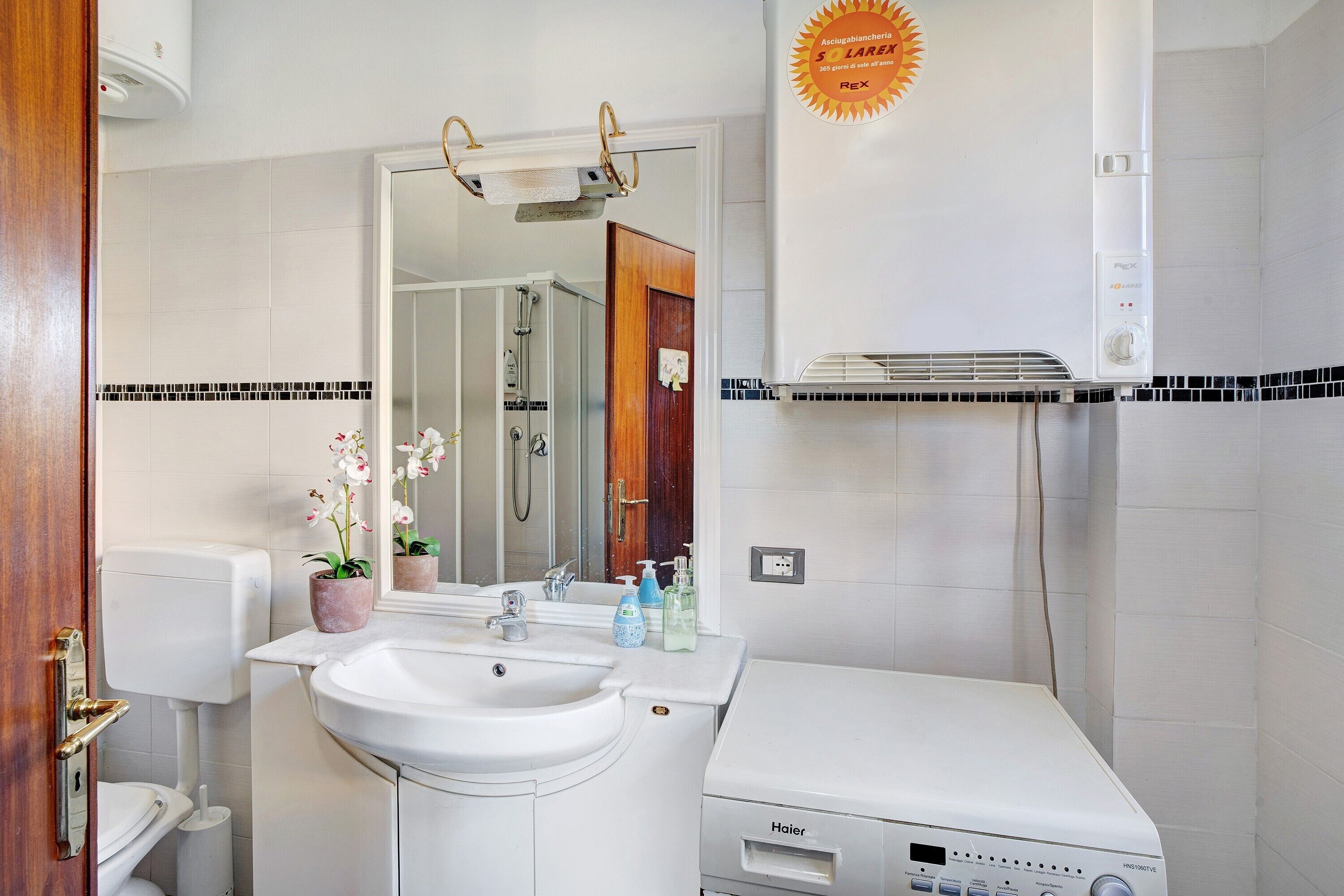 Une salle de bain avec un lavabo blanc, un miroir, des toilettes et une douche.