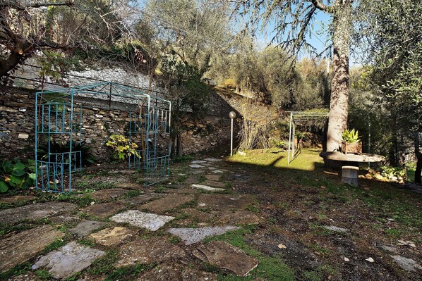 A stone pathway leading to a garden area with a metal structure and a bench.