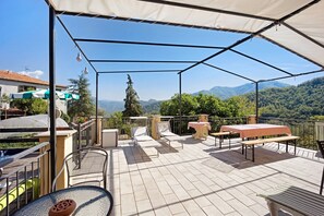 Une terrasse extérieure couverte, aménagée avec des sièges et une table, et offrant une vue sur les montagnes.