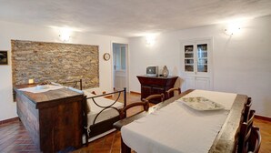 Habitació amb llit, un taulell de fusta, paret de pedra, televisió i un armari.
