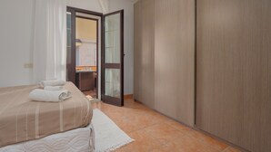 Ein Schlafzimmer mit Bett, Kleiderschrank, Bad und einer Tür zu einem weiteren Raum.