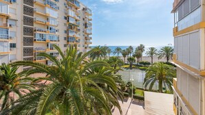Un immeuble à plusieurs étages doté de balcons, de palmiers et offrant une vue sur la mer.
